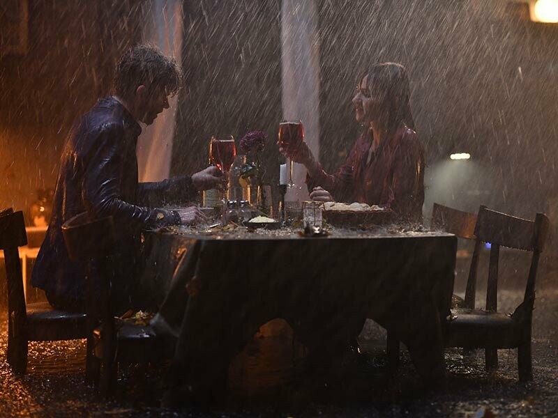 Pärchen sitzt zuhause bei einem romantischen Dinner. Beide sind komplett nass, da es im Haus ohne Dach regnet. Ausschnitt aus dem PREFA Werbespot 2019
