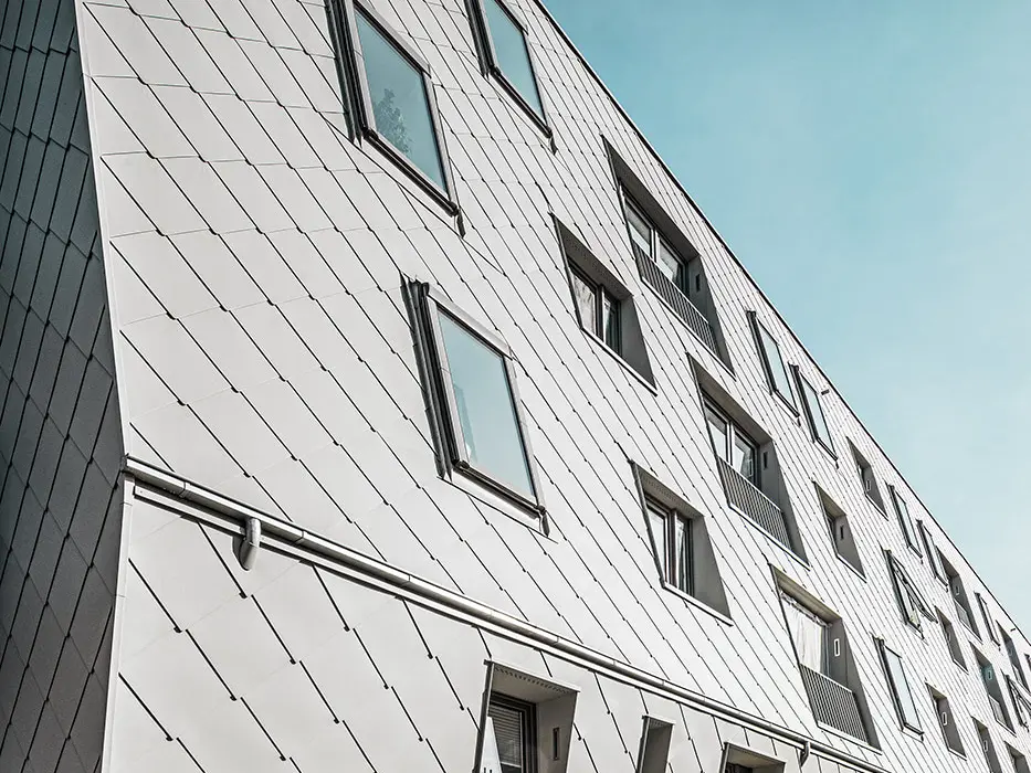 Im Bild sind die zinkgrauen PREFA-Wandrauten in P.10 zu sehen, welche die Fassade des Gebäude schmücken.