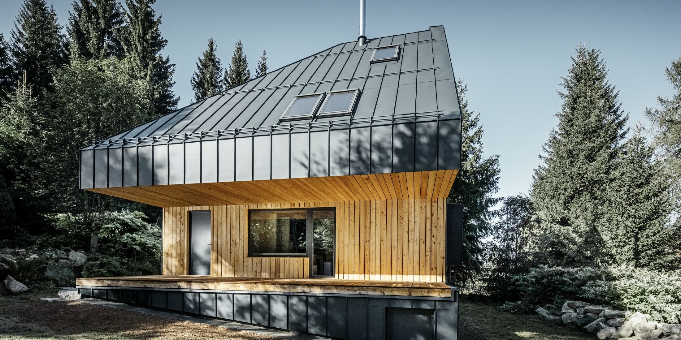 Architektonisches Einfamilienhaus im Wald, das imposante Dach wurde mit Prefalz Aluminium von PREFA in Anthrazit verkleidet. Die Untersicht sowie die Fassade ist mit Holzpaneelen verkleidet.