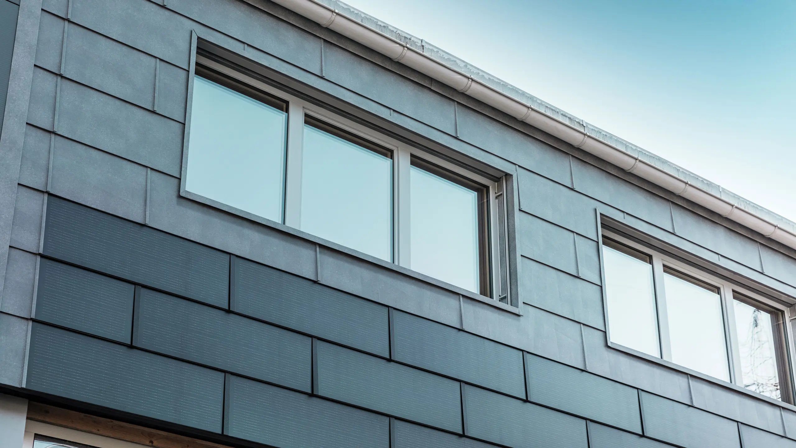 Die Fassadenfläche des Firmengebäudes wurde mit den innovativen Solardachplatten, kombiniert mit den FX.12 Fassadenpaneelen von PREFA, bekleidet.
