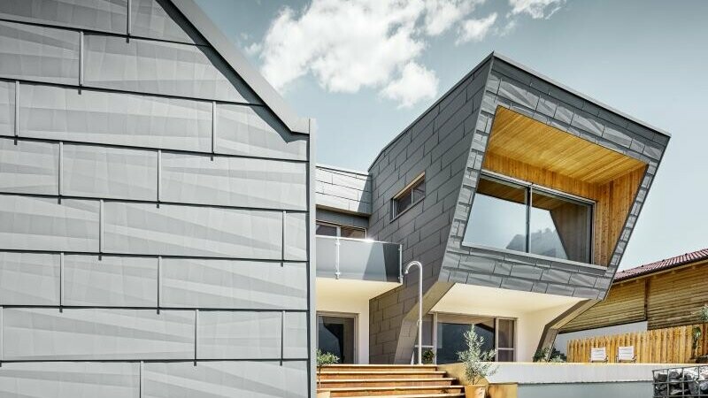 Für die Fassade dieses Einfamilienhauses wurden PREFA Aluminiumpaneele in P.10 Hellgrau mit Holzelementen kombiniert