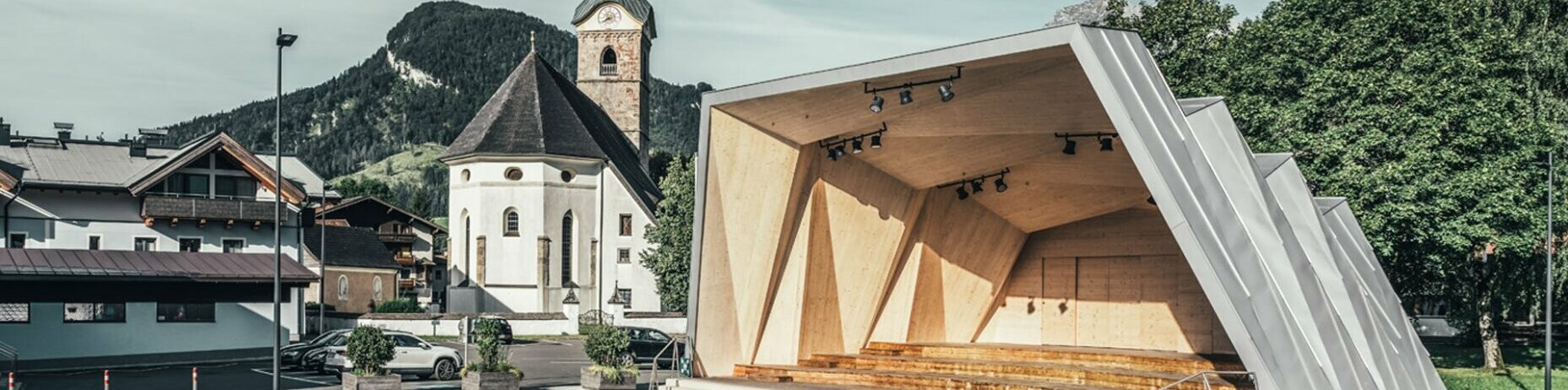 Gesamtbild des Musikpavillon von Kirchdorf und im Hintergrund die Kirche der Gemeinde