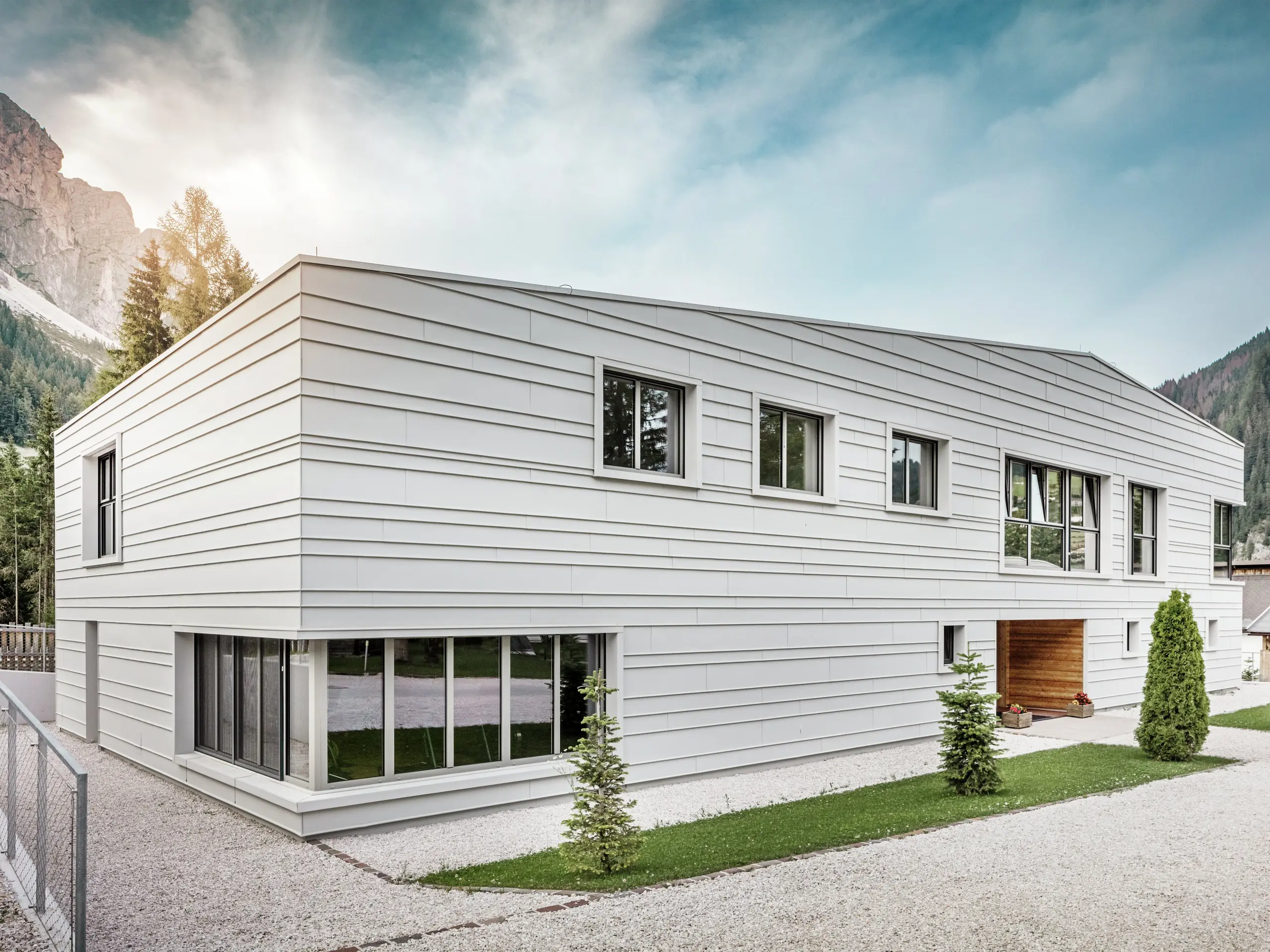 Die moderne Fassade der Kaserne „Tempesti“ in Südtirol besticht durch ihre klare Geometrie und die hochwertigen Stehfalzpaneele aus PREFALZ Aluminium in der Farbe P.10 Prefaweiß. Das verwendete Aluminium reflektiert das Licht, reguliert das Raumklima und bietet langfristigen Schutz. Ein besonderes optisches Highlight ist der holzgetäfelte Eingang, der der strengen militärischen Umgebung Wärme und Offenheit verleiht.