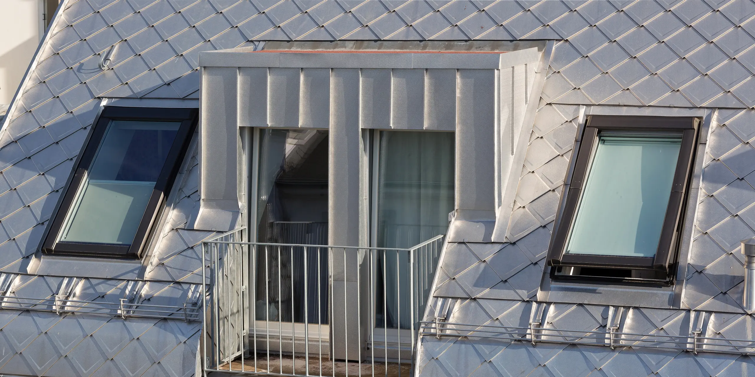 Das Dach dieses modernen Wohngebäudes in Hamburg wurde mit PREFA Dachrauten 29 × 29 in der Farbe Naturblank gedeckt. Dadurch erhält es eine auffällige, metallische Optik. Besonders hervorzuheben ist der charmante Balkon, der sich harmonisch in das Design des Daches einfügt.