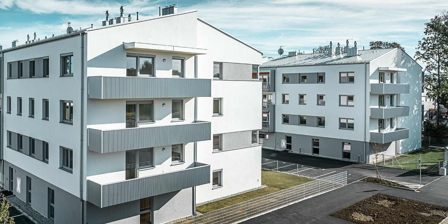 Moderne Wohnhausanlage mit weißer Fassade und Balkonen mit PREFA Zackenprofil in Silbermetallic