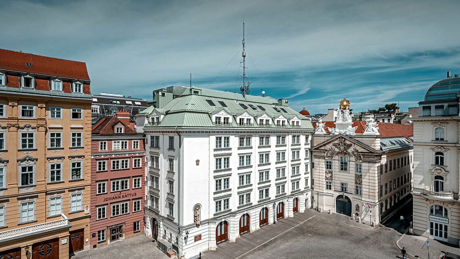 Blick auf die zentrale Feuerwache am Hof in Wien, umgeben von mehreren Gebäuden. Das Dach ist mit Prefalz in P.10 patinagrün eingedeckt.