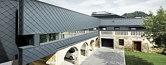 Ein altes Steingemäuer kombiniert mit modernen Fassadenelementen aus PREFA Wandrauten in P.10 Anthrazit