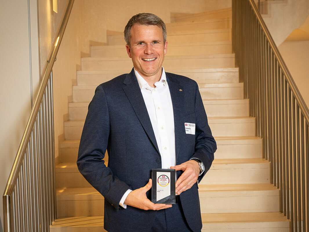 Tobias Götz, Geschäftsführer von PREFA, steht vor einer Treppe und präsentiert die Auszeichnung des Life & Living Award 2026.