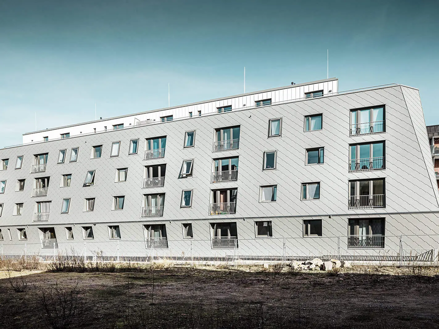 Das Bild zeigt das Haus im Harburger Binnenhafen bei Tag, welches mit PREFA Wandrauten 44x44 und Prefalz eingedeckt wurde.