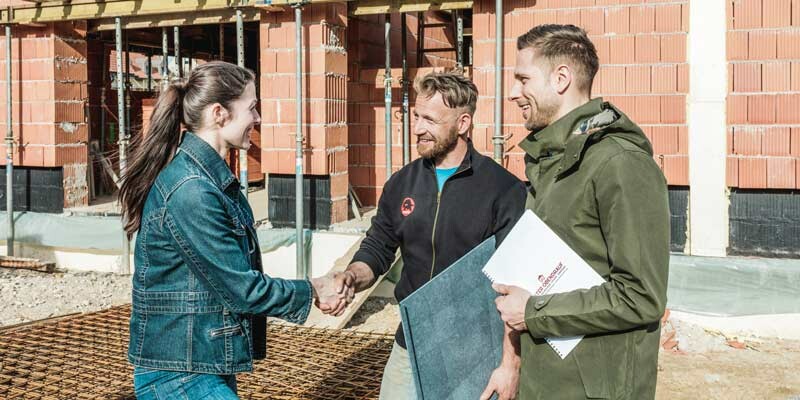 Zufriedene Kunden im Gespräch mit einem Handwerker auf der Baustelle