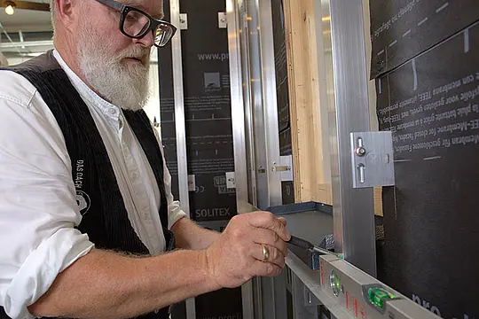 PREFA-Techniker Tom Weiß misst die Höhe des Fensterblechs ab.
