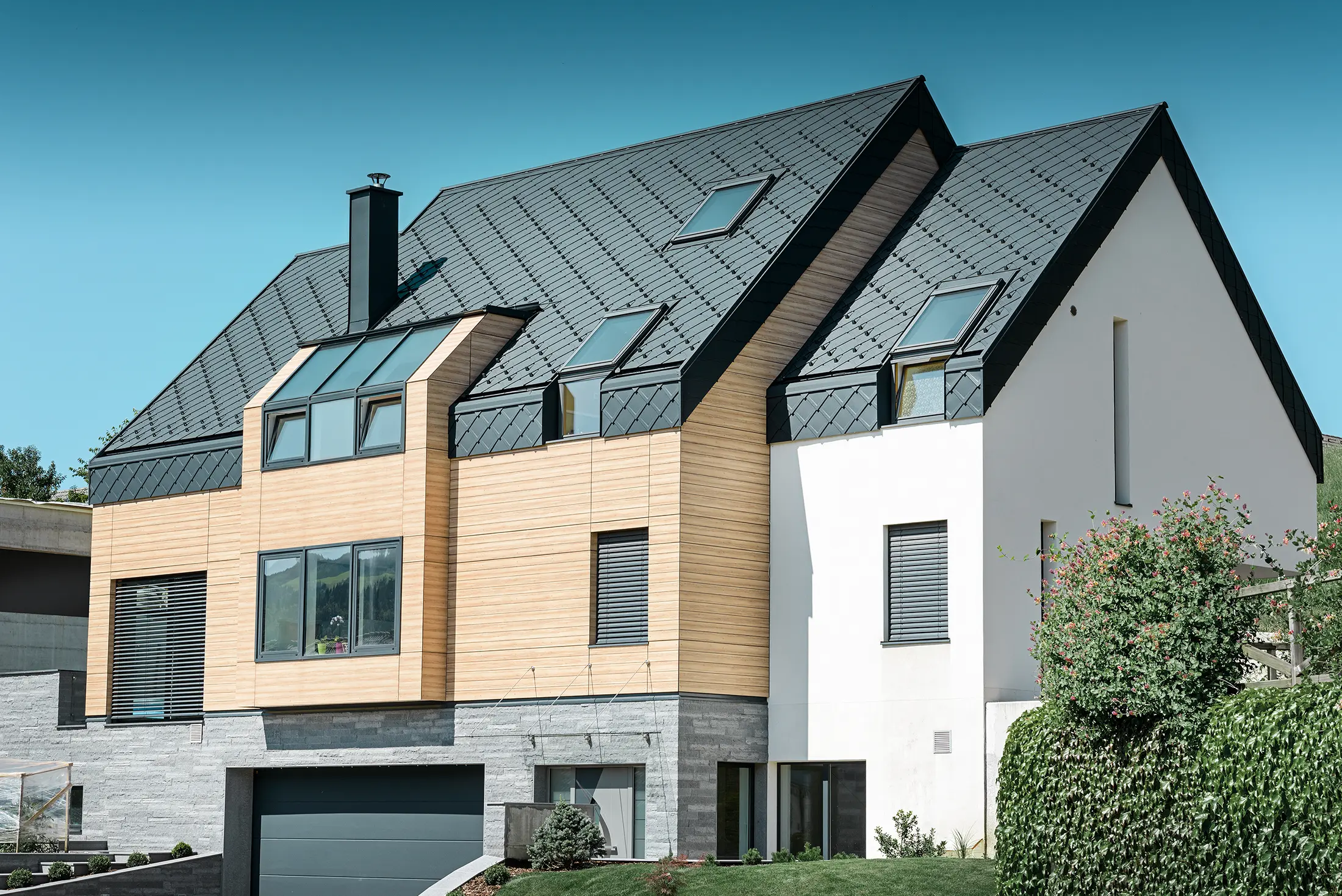 Zeitgemäßer Neubau, bei dem sich die Dachhaut auch über den oberen Teil der Fassade zieht, als Dacheindeckung wurde die Alu-Dachraute in Anthrazit verwendet