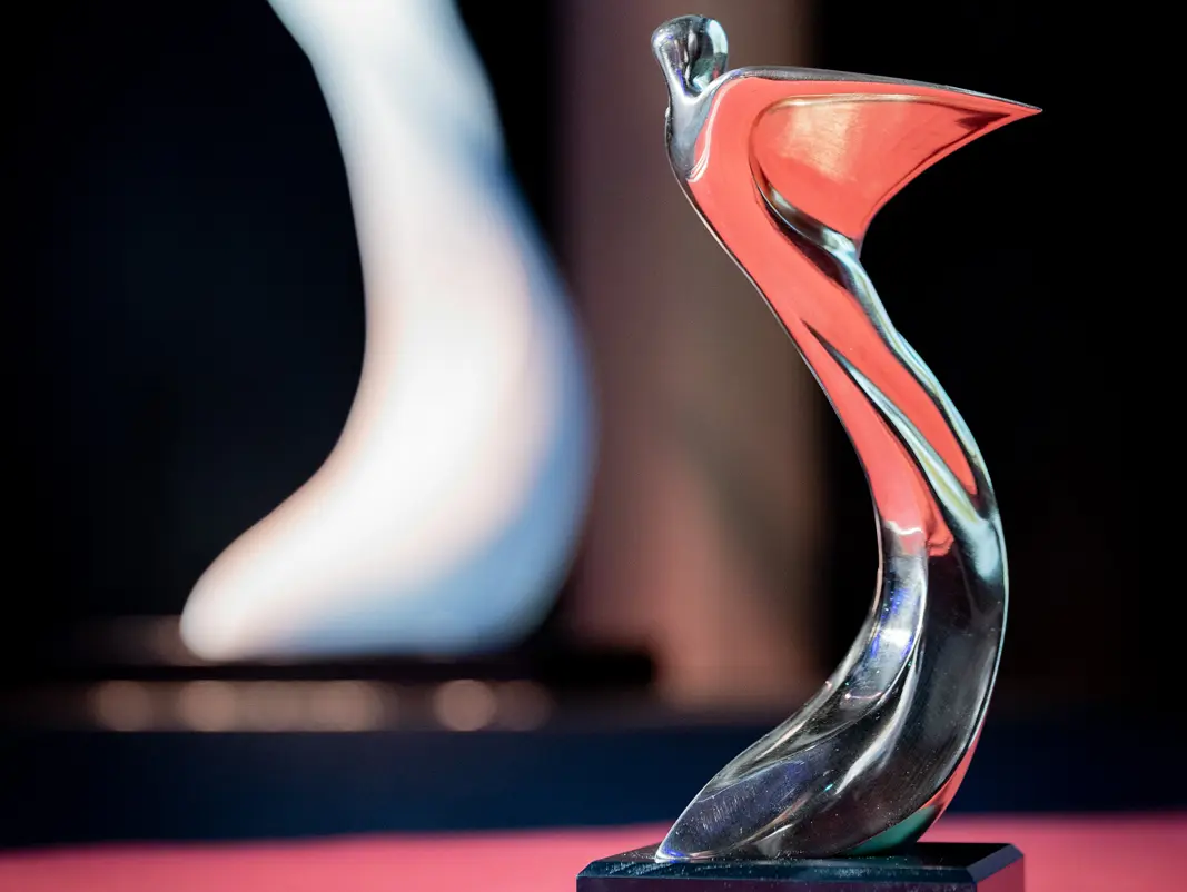 Detailaufnahme der silbernen Trophäe des Architects' Darling Awards 2023, welche auf der Bühne mit rotem Teppich steht.