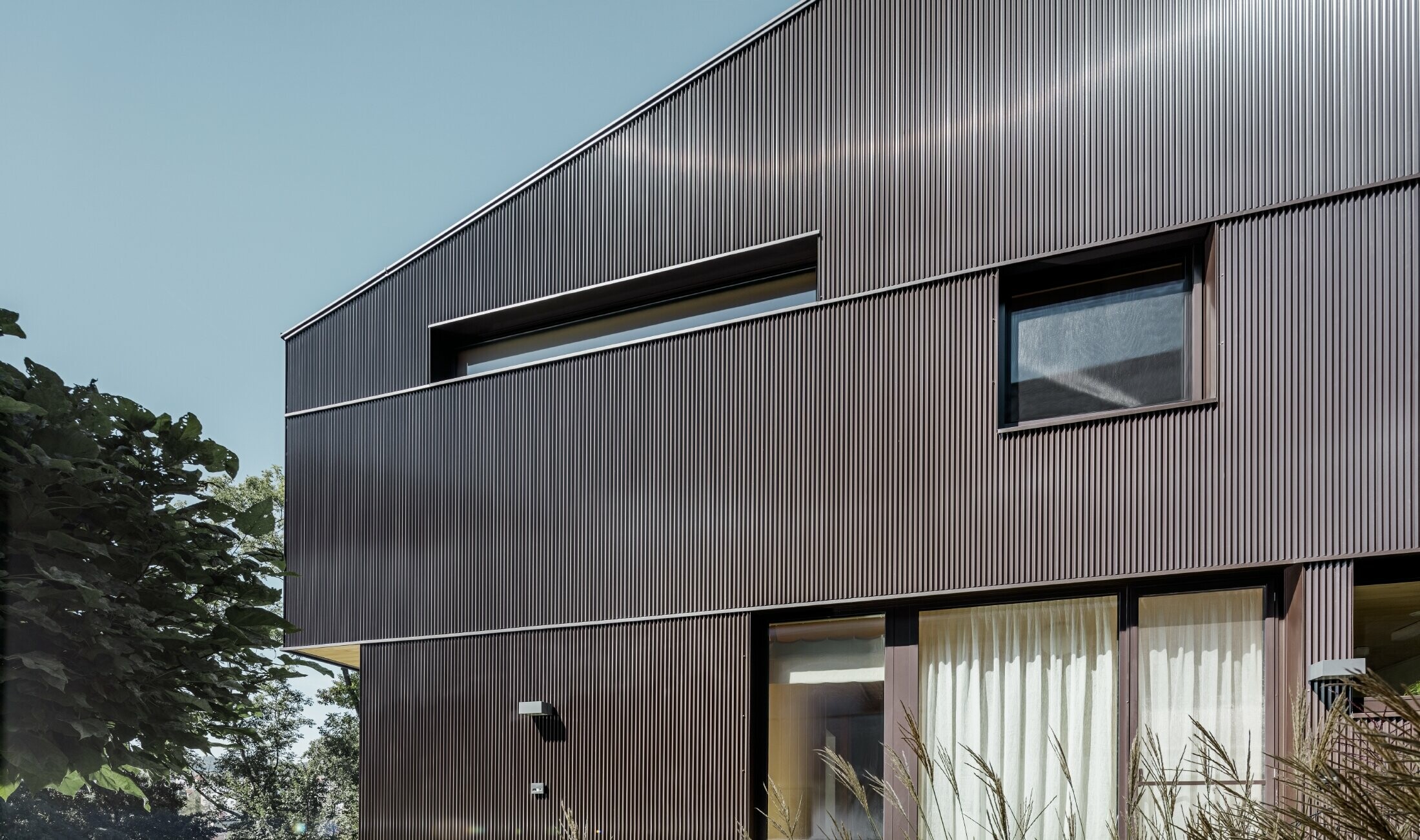 Modernes Einfamilienhaus mit einer Fassadenbekleidung von PREFA - Zackenprofil in Braun.