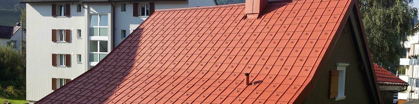 Einfamilienhaus mit Walmdach aus Aluminiumschindeln von PREFA in Ziegeloptik mit Schneestoppern.