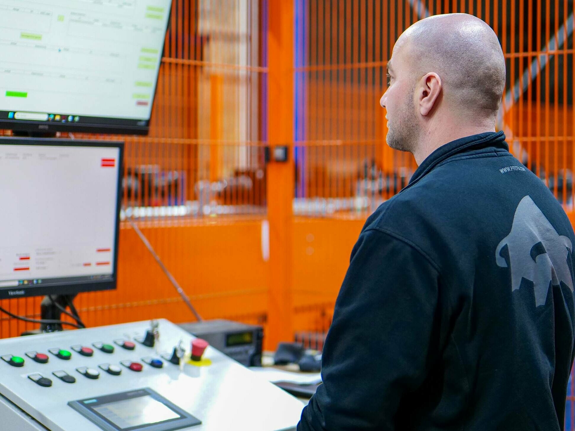 PREFA Produktionsmitarbeiter steht an der Maschine und überwacht die Abläufe.