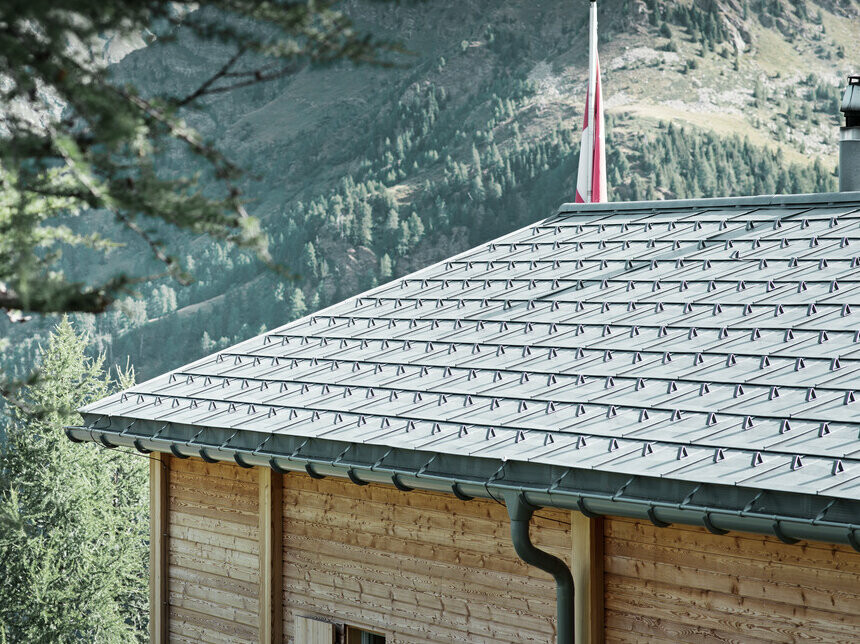 Schweizer Hütte mit der PREFA Dachplatte eingedeckt und mit der PREFA Hängerinne, die mit dem Überbügel befestigt ist.
