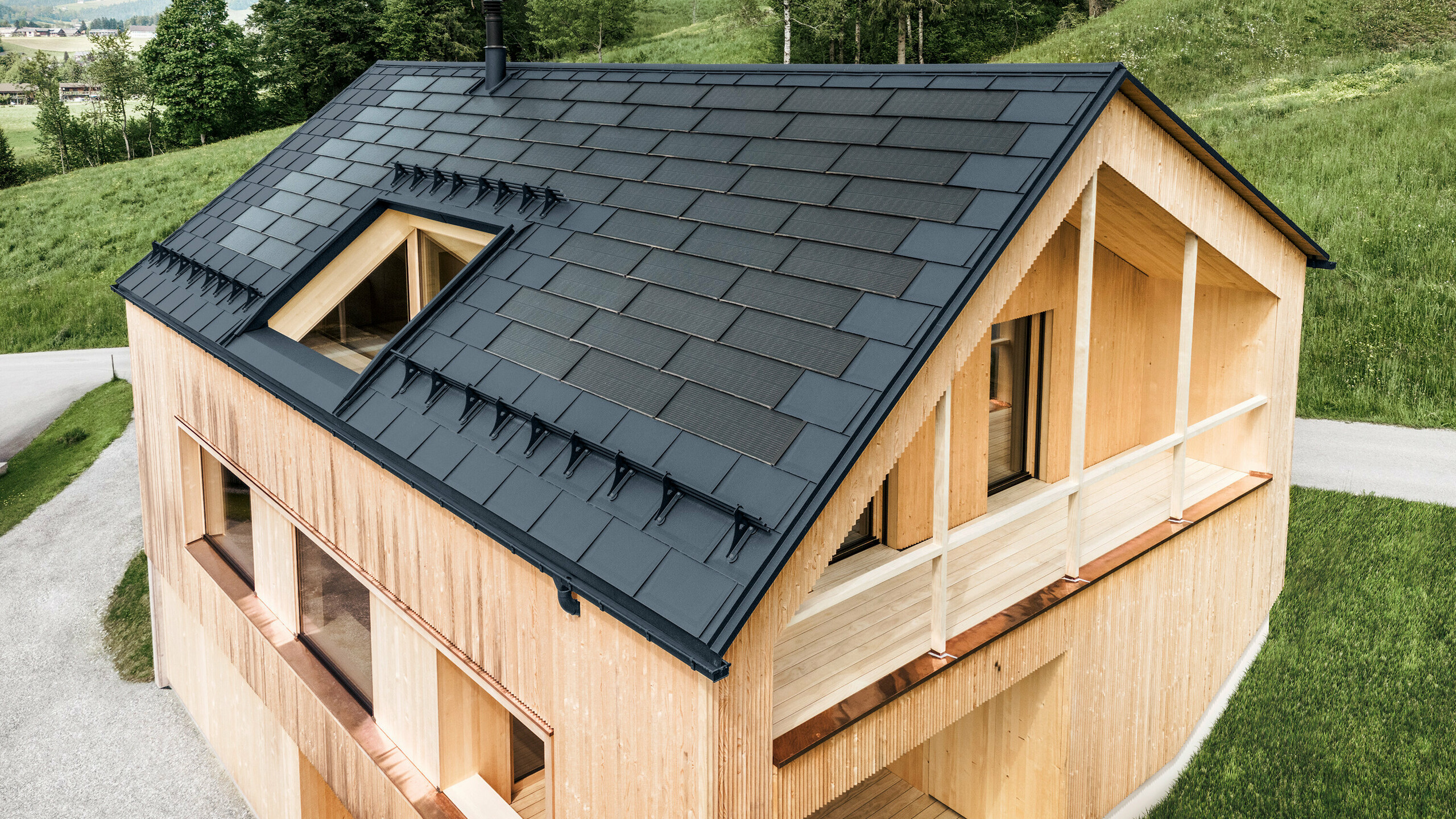 Einfamilienhaus im österreichischen Ort Egg mit der PREFA Solardachplatte und der Dachplatte R.16 in Anthrazit, kombiniert mit einer Holzfassade