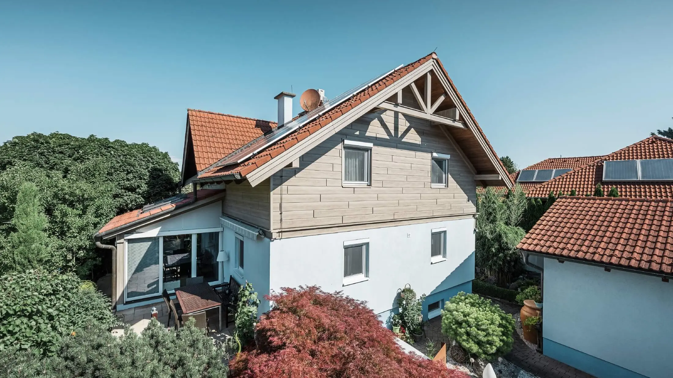 Fassade eines Einfamilienhauses, das im Obergeschoss mit Holzoptik Sidings in der Farbe Eiche beige-grau verkleidet wurde