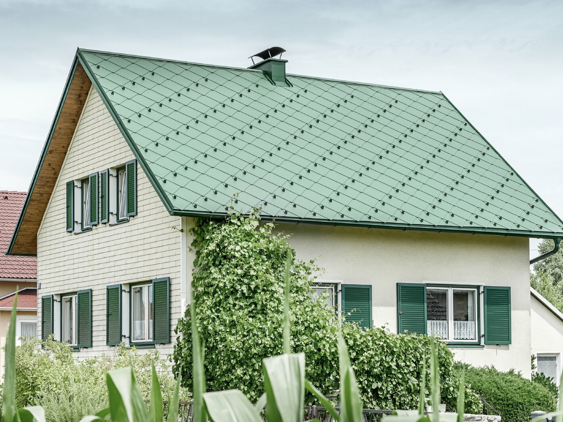 Klassisches Einfamilienhaus mit Satteldach mit einer Dacheindeckung aus Aluminium von in moosgrün mit grünen Fensterläden