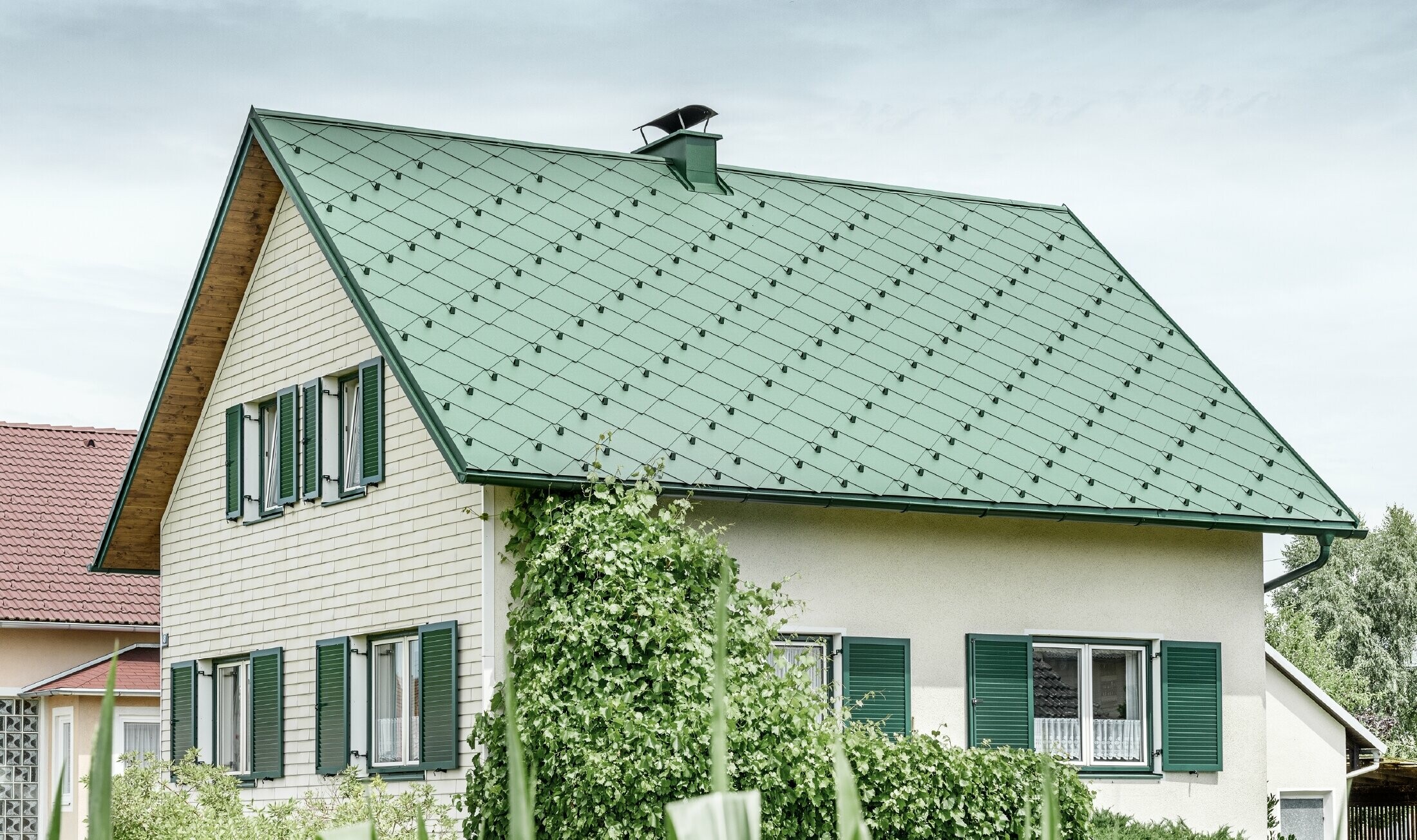 Klassisches Einfamilienhaus mit Satteldach mit einer Dacheindeckung aus Aluminium von in moosgrün mit grünen Fensterläden