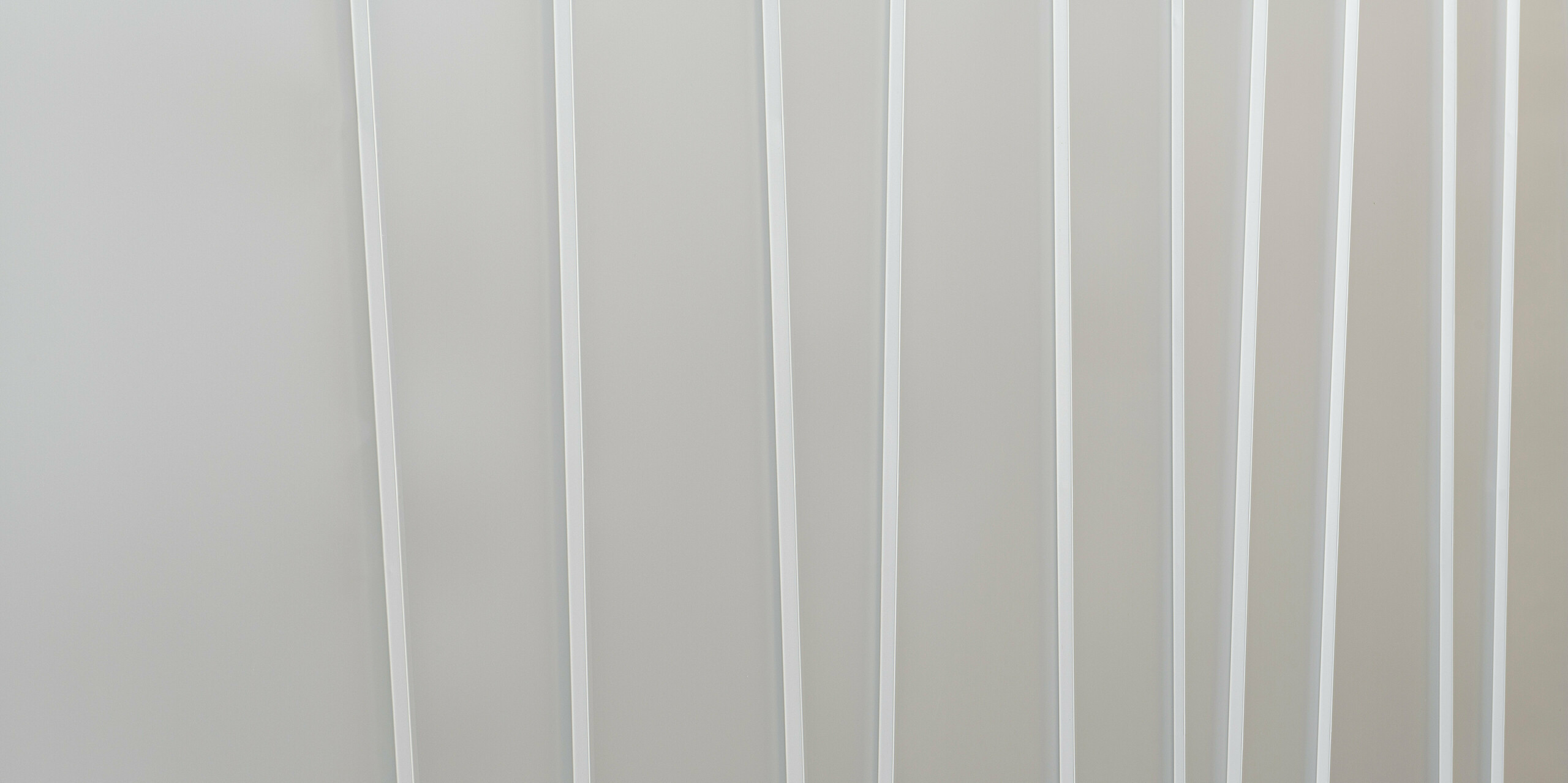 Nahaufnahme eines modernen Fassadensystems aus PREFALZ in Hellgrau mit verschiedenen Scharenbreiten. Die klare und minimalistische Textur vermittelt ein Gefühl von Ordnung und zeitgemäßem Design.