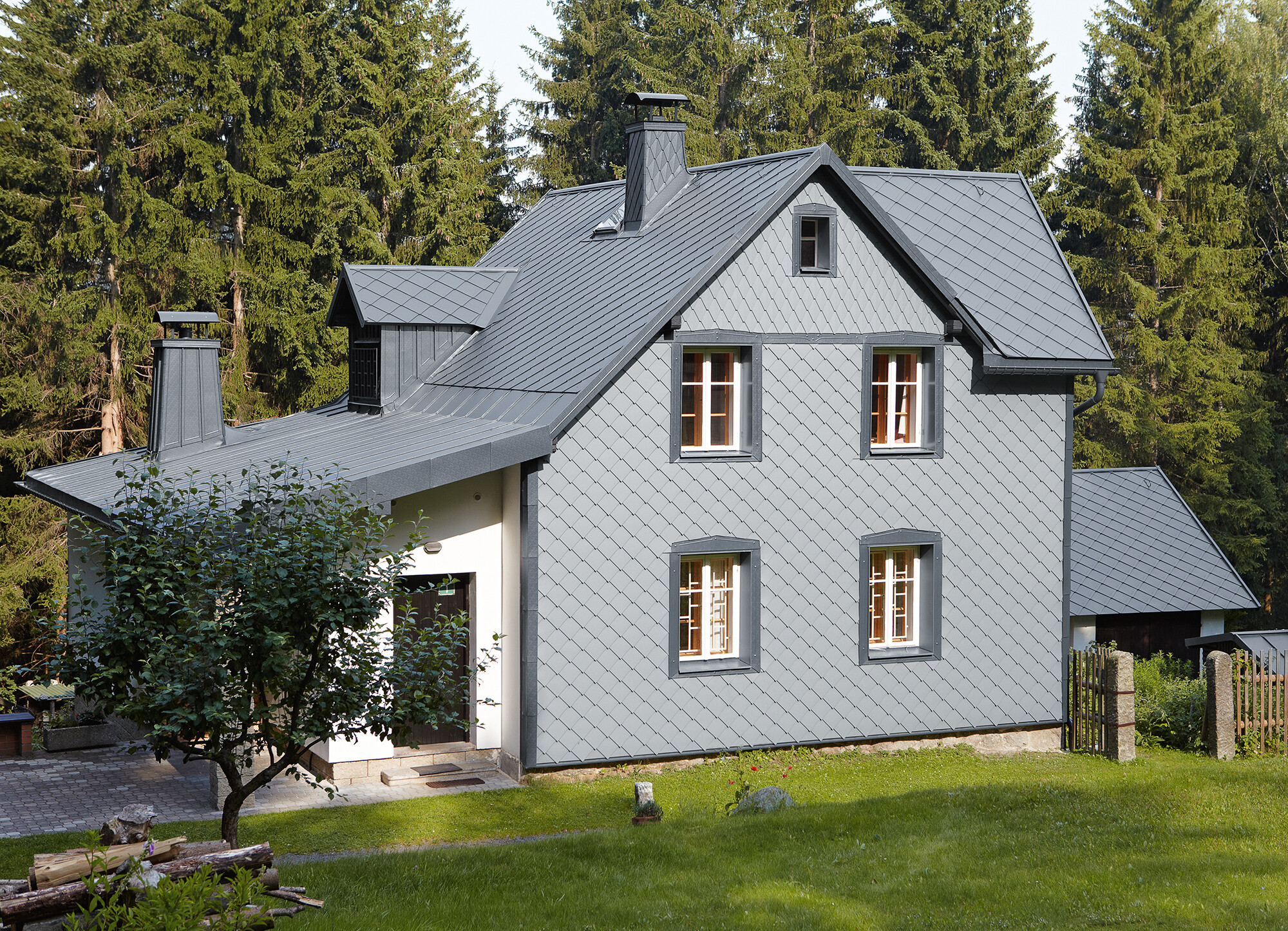 Einfamilienhaus in Waldlage mit witterungsbeständiger PREFA Aluminiumfassade in Hellgrau.