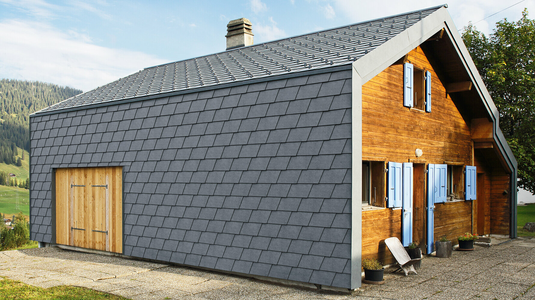 Modernes Einfamilienhaus verkleidet mit PREFA Wandschindeln in der Farbe P.10 Steingrau und Holzelementen.