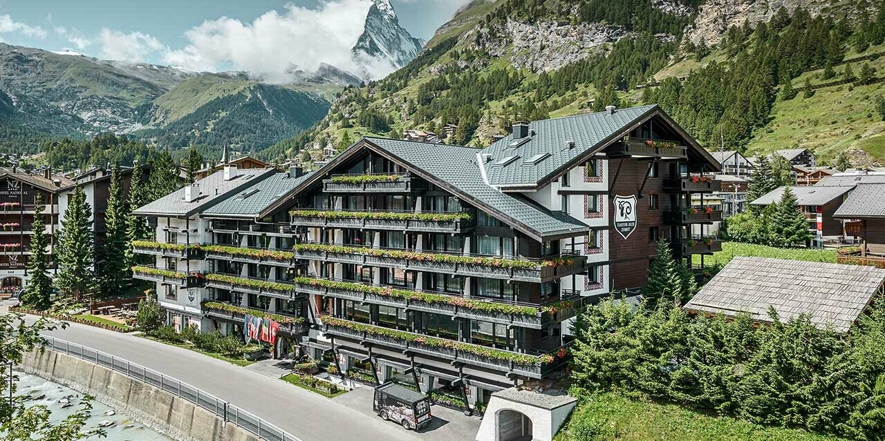 Hotelalpenhof in Zermatt mit dem Matterhorn im Hintergund, Balkonen, dunkler Holzfassade und einem PREFA Aluminiumdach in anthrazit