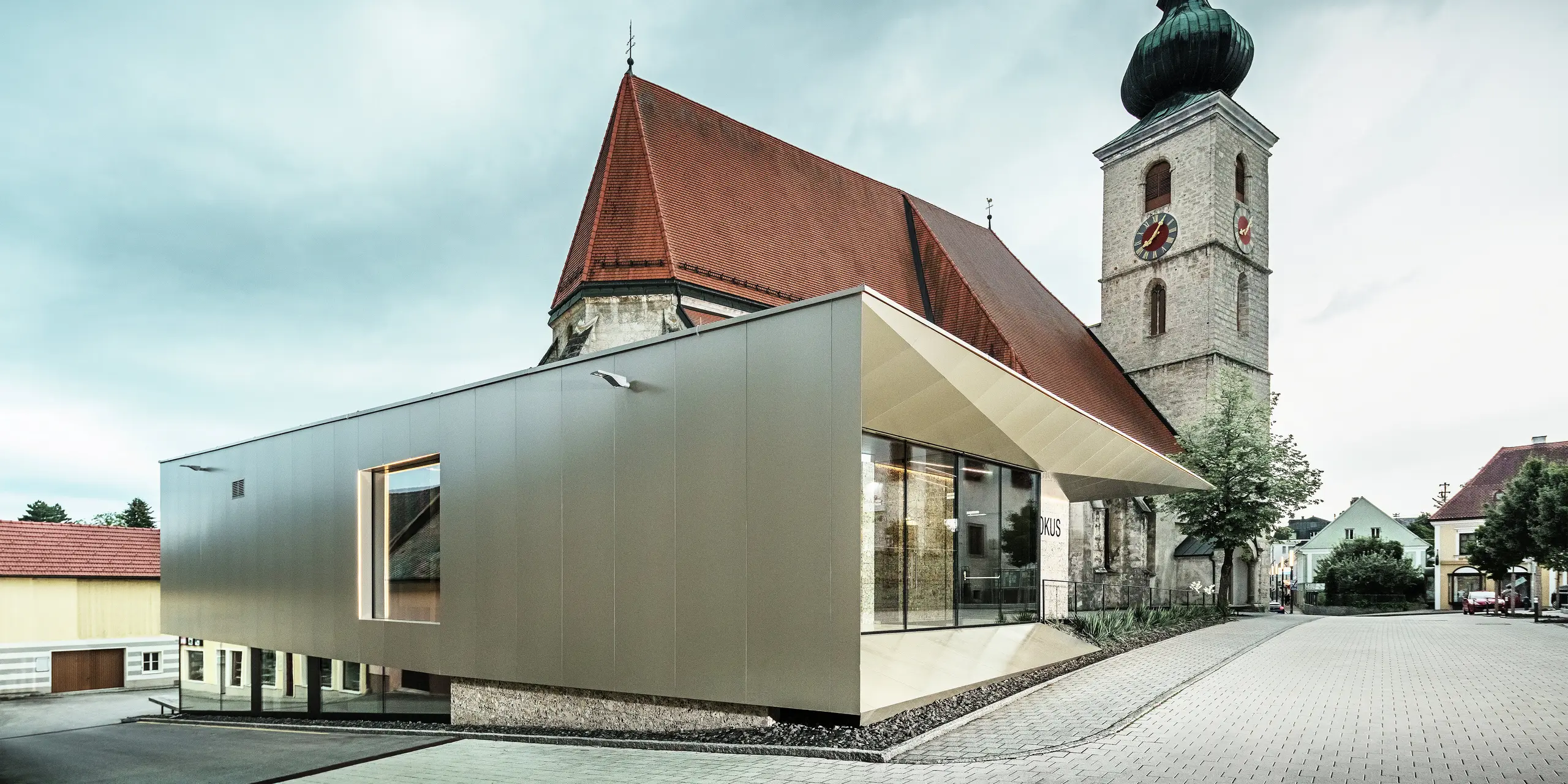 Die seitliche Ansicht zeigt den filigranen Dachüberstand, realisiert mit hochwertigen PREFA Aluminium Verbundplatten. Die exakte Verarbeitung ermöglicht eine moderne Optik mit klaren Linien und unterstreicht die architektonische Verbindung zwischen Alt und Neu.