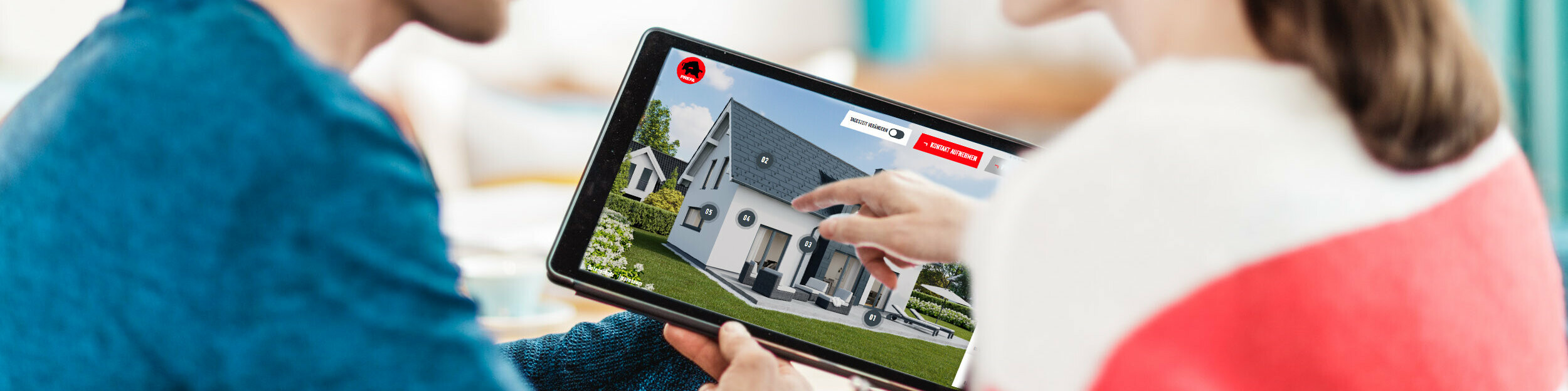 Ein Paar sitzt gemeinsam am Tisch und betrachtet auf einem Tablet die digitale Darstellung eines Hauses mit Dach, Fassade und Solar-Elementen aus Aluminium – im Kontext des PREFA Ratgebers zu Dach, Fassade und Solar für Hausbau und Sanierung.