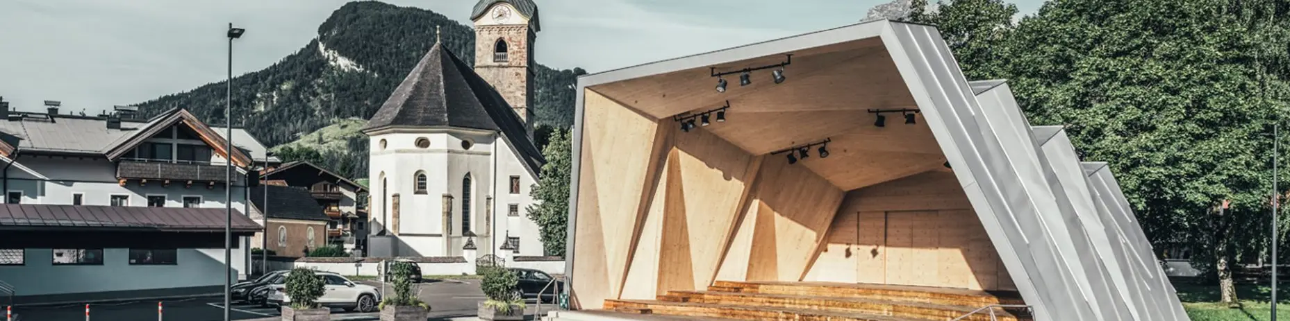 Gesamtbild des Musikpavillon von Kirchdorf und im Hintergrund die Kirche der Gemeinde