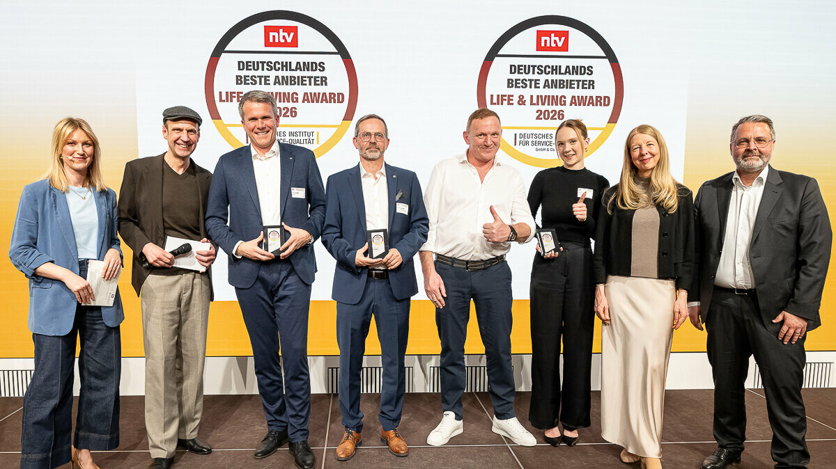 Tobias Götz, Geschäftsführer von PREFA, steht gemeinsam mit weiteren Preisträgerinnen und Preisträgern auf der Bühne beim Life & Living Award 2026 und präsentiert die erhaltene Auszeichnung.