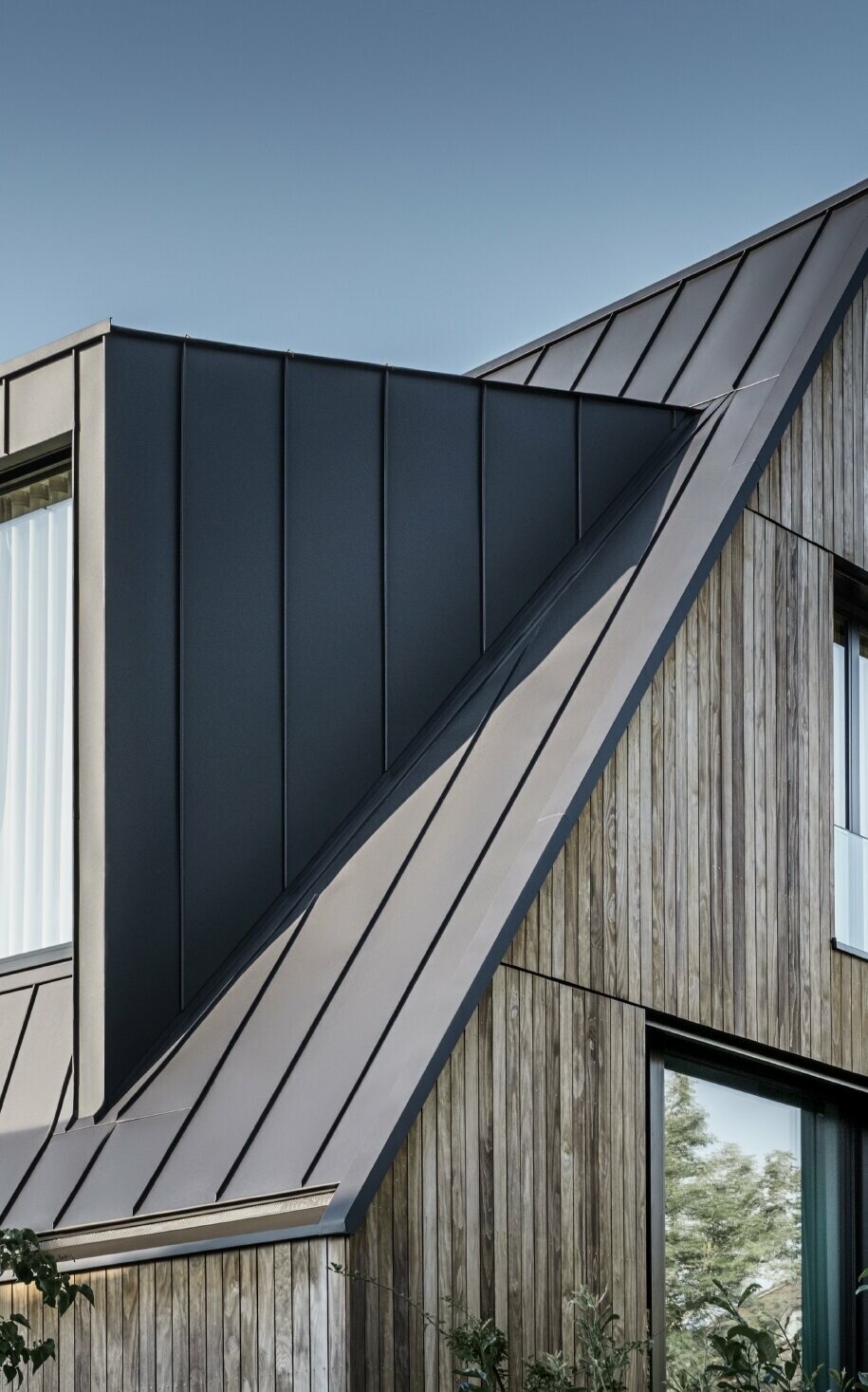 Steiles Satteldach mit großer Gaube, eingedeckt mit PREFALZ von PREFA in Anthrazit Stehfalzdach kombiniert mit Holzfassade