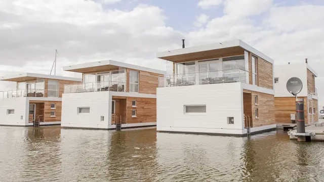 Drei moderne schwimmende Häuser in Stralsund liegen direkt im Wasser des Yachthafens und beeindrucken mit klarer, geradliniger Architektur. Die PREFA Sidings in P.10 Prefaweiß setzen markante Akzente und bilden einen eleganten Kontrast zu den warmen Holzfassaden. Die langlebigen, korrosionsbeständigen Aluminiumfassaden sind ideal für das maritime Umfeld und überzeugen durch ihre Witterungsbeständigkeit sowie Pflegeleichtigkeit.