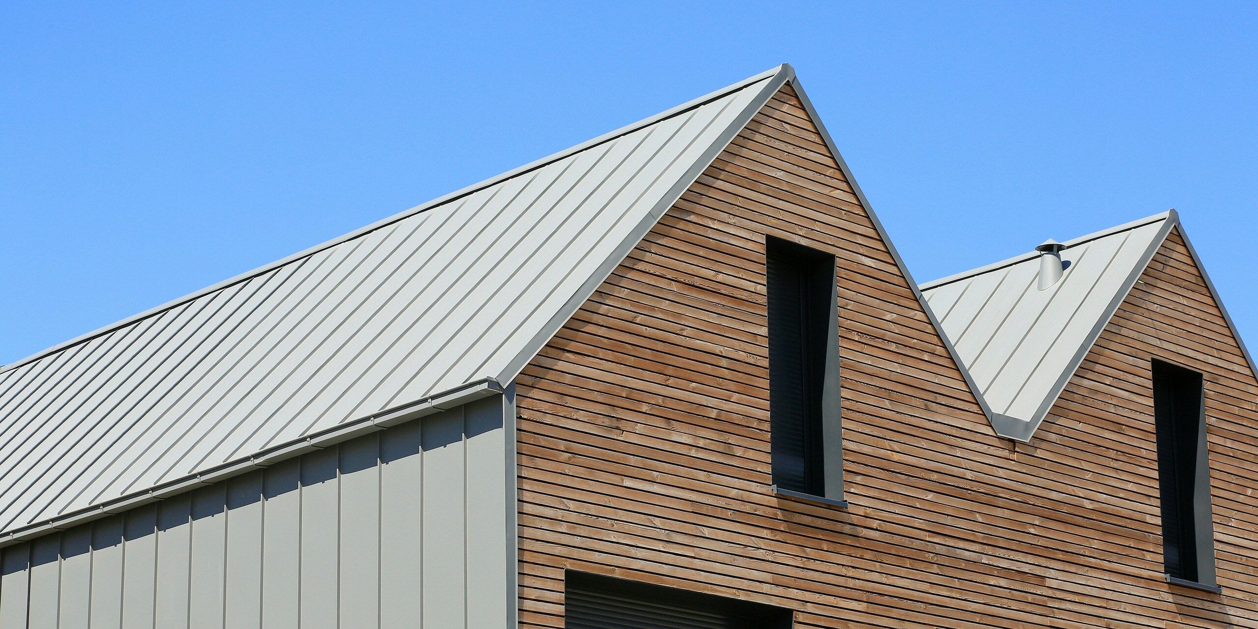 PREFALZ in Hellgrau zieht sich über die Fassaden und Satteldächer einer Reihenhaus-Siedlung in Mundolsheim. Die einheitlichen Gebäudehüllen aus Aluminium schaffen ein harmonisches Gesamtbild.