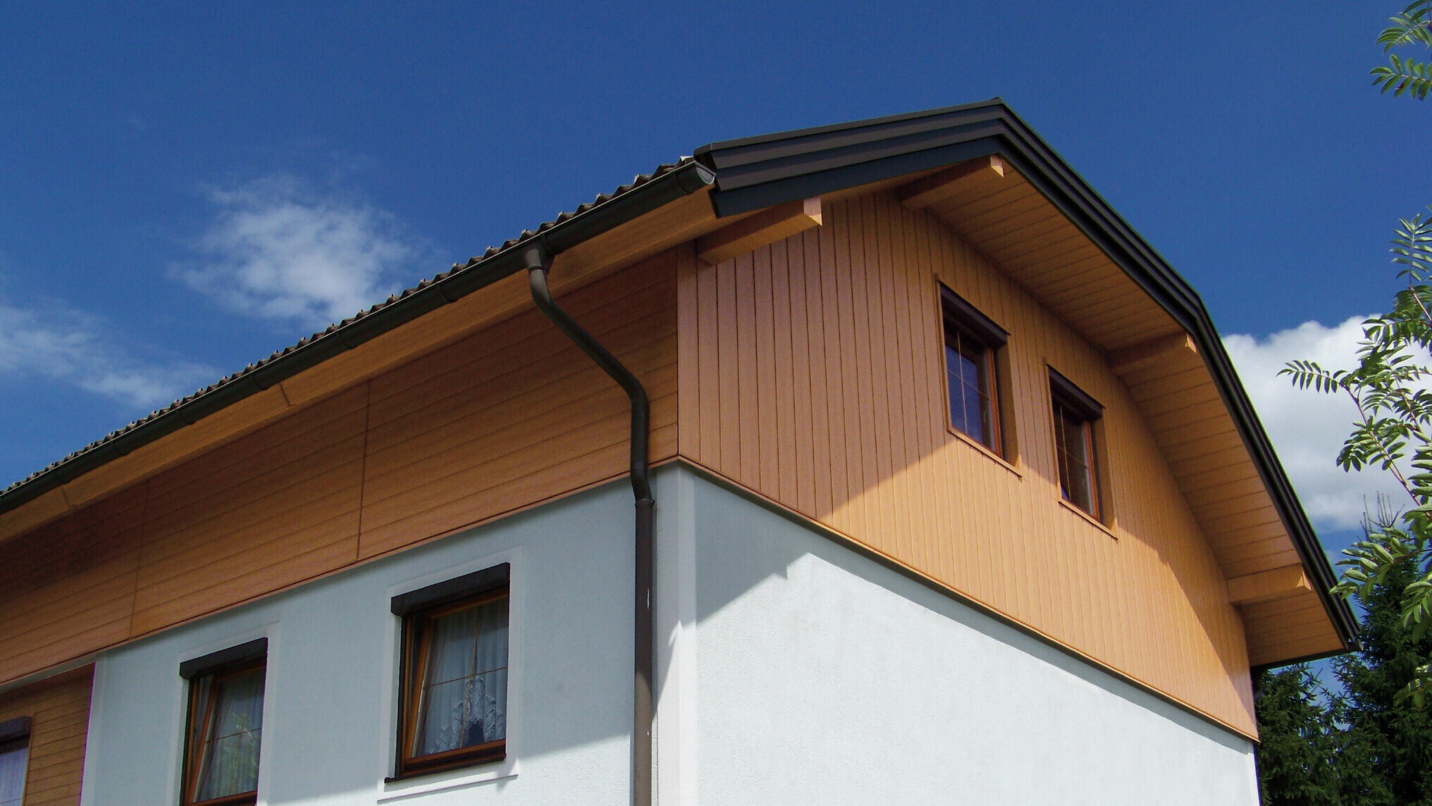 Großes Einfamilienhaus mit Krüppelwalmdach und einer Giebelverkleigung mit den PREFA Sidings in Holzoptik (Farbe Eiche natur)
