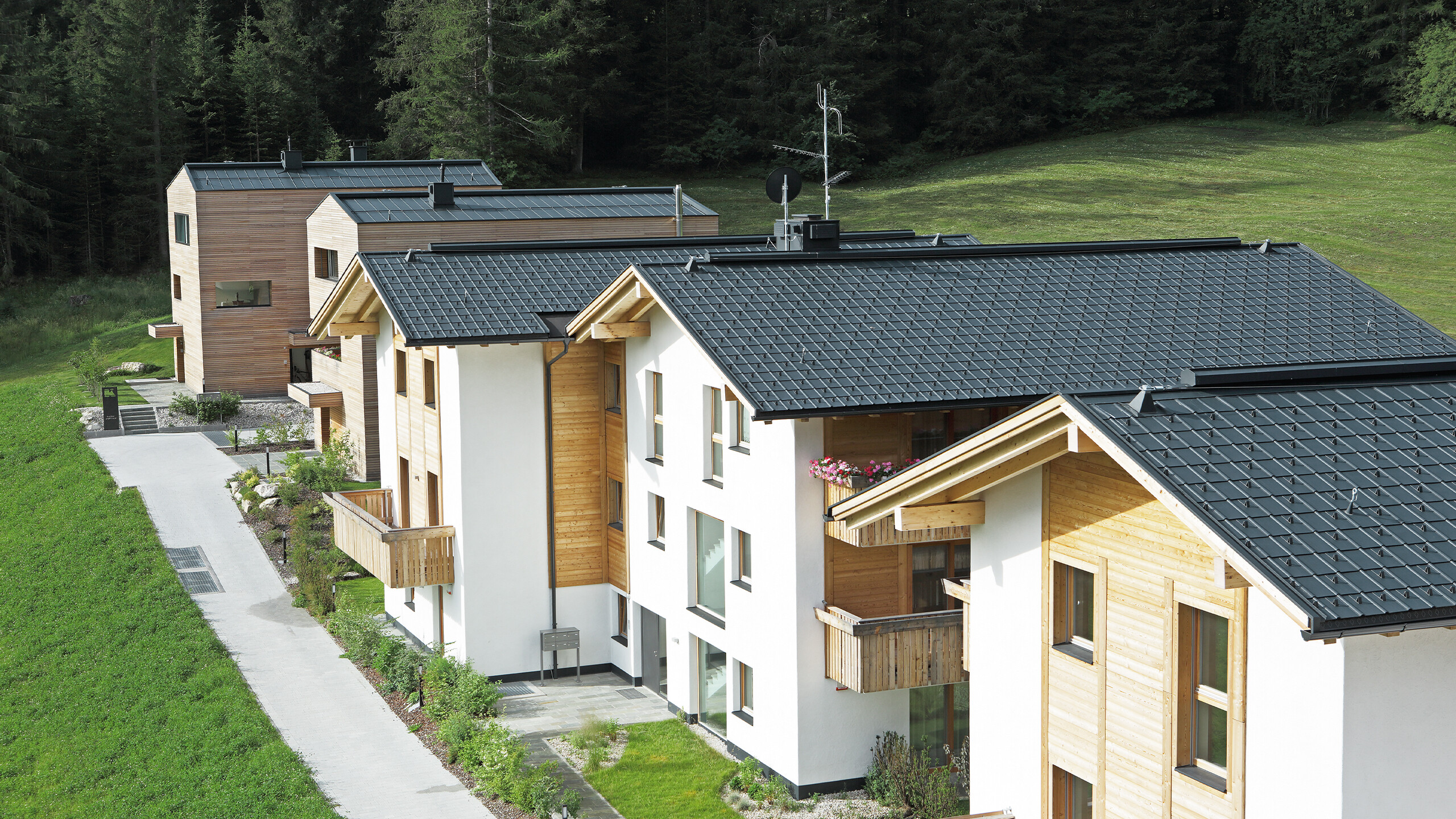 Aufnahme der fünf Wohnbauten in Corvara, eingedeckt mit der PREFA Dachplatte und Stehfalz in Anthrazit aus sturmsicherem Aluminium