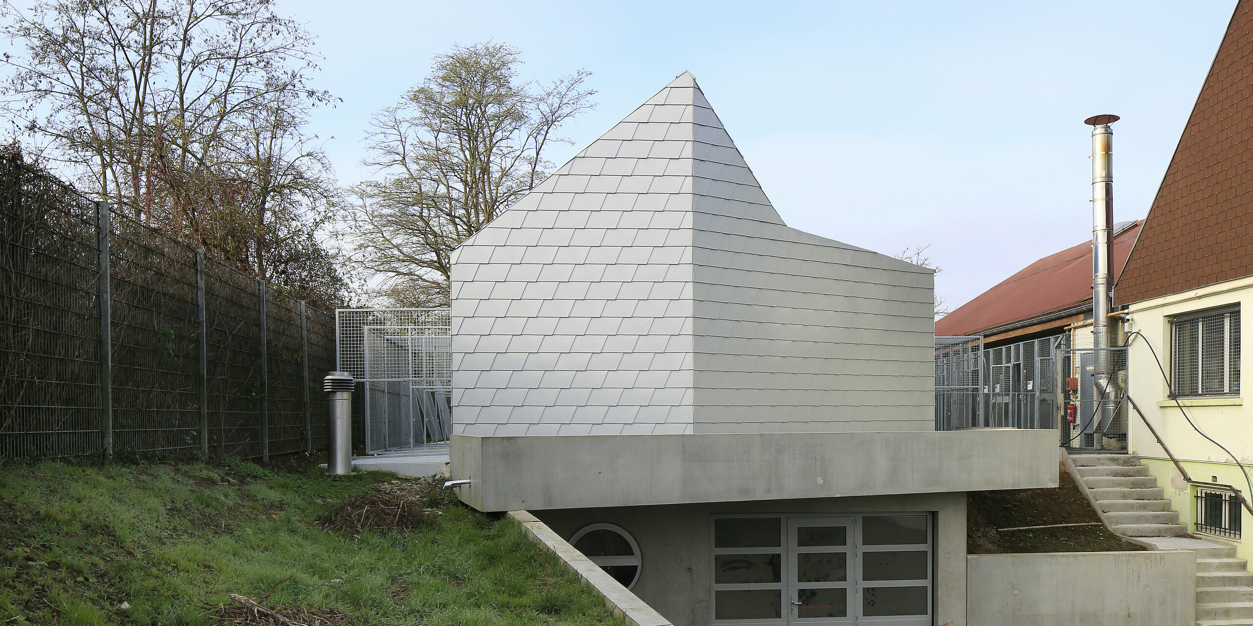 Zugang zum Tierschutzverein in Mullhouse mit einer auffälligen Gebäudehülle aus PREFA Dach- und Wandschindeln in Silbermetallic