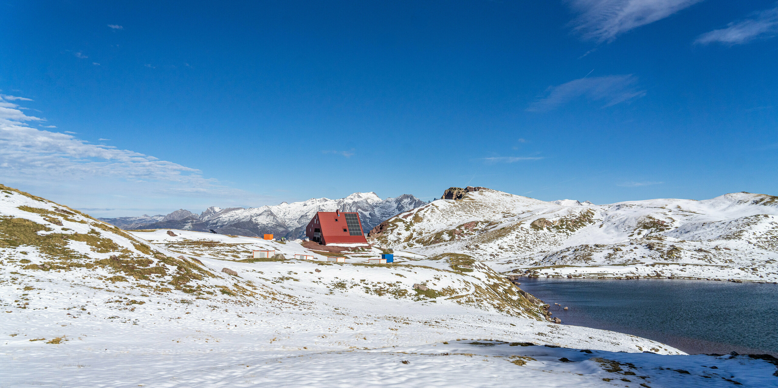Blick aus der Ferne auf Schutzhütte Arlet im Pyrenäen-Nationalpark mit Schnee und Berge im Hintergrund